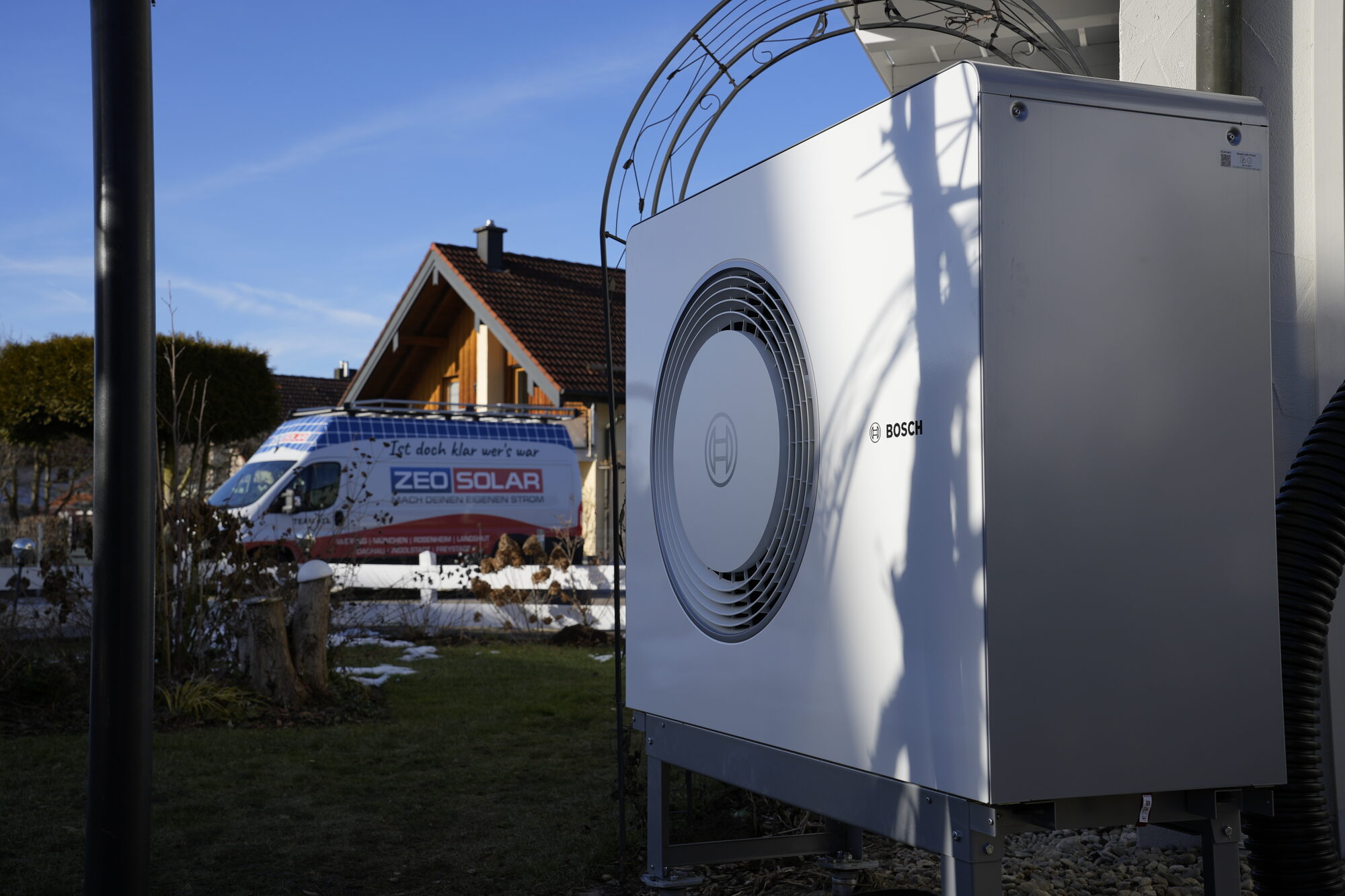 Von ZEO SOLAR installierte Bosch-Wärmepumpe an einem Einfamilienhaus, im Hintergrund das Firmenfahrzeug
